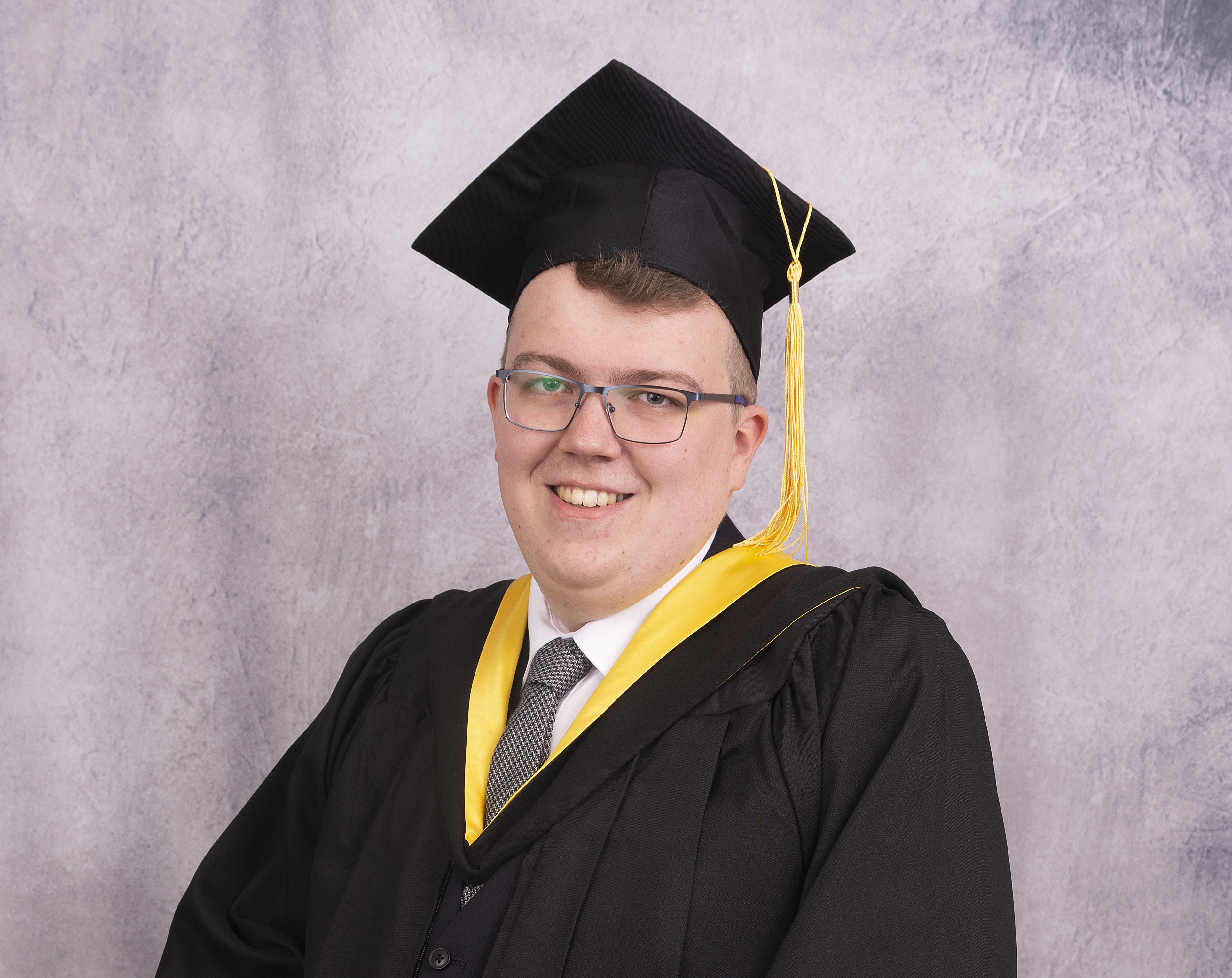Nathan Doherty smiling in a university cap and gown